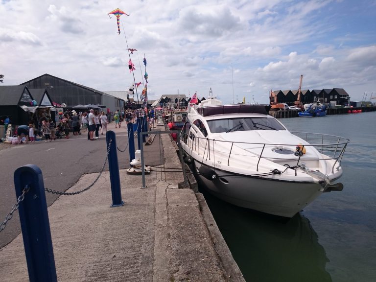 Song and Dance moored on a harbour wall on a summer day