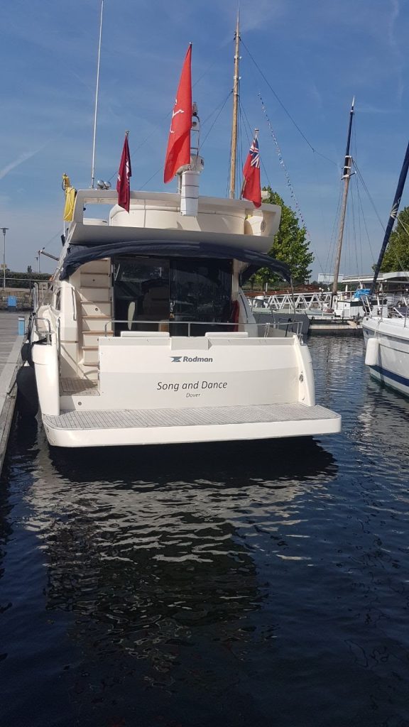 The stern of Song and Dance at her marina berth, flags flying