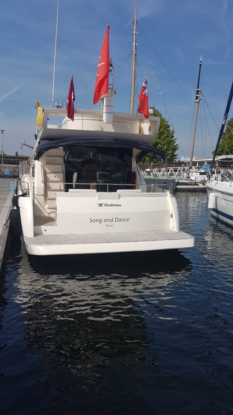 The stern of Song and Dance at her marina berth, flags flying